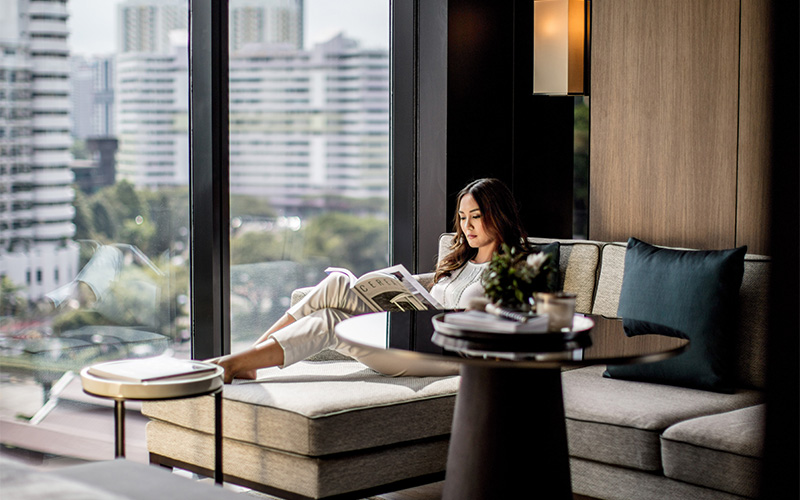 Woman relaxing in InterContinental Robertson Quay suite.