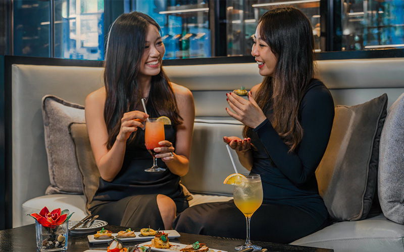 Women enjoying cocktails at InterContinental Singapore Robertson Quay club lounge.