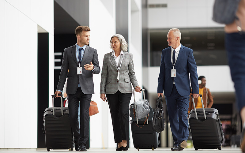 Business travelers walking with luggage at a hotel lobby.